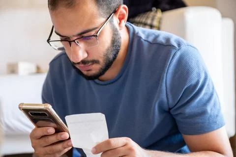 Young bearded man making call while holding receipts Stock Photos