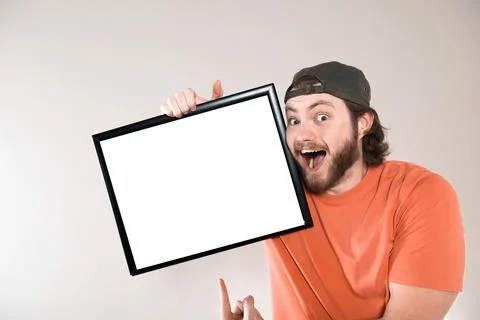Young bearded man making funny face, holding a blank sign board. Studio shot  Foto stock
