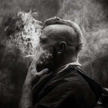Young bearded man with a mohawk sitting at barbershop and smoking a cigarette Stock Photos