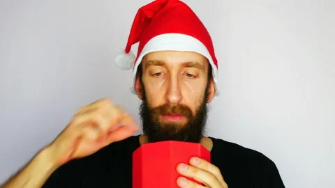 A young bearded man opens a Christmas gift box but finds many protective masks Stock Footage 142157951
