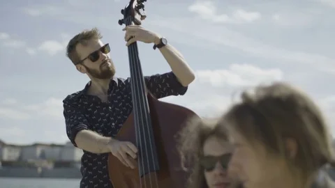 Young Bearded Man Playing Double Bass at the River Bank Stock Footage 81513996
