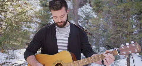 Young Bearded Man Playing Guitar in the Snowy Woods Stock Footage 87265866
