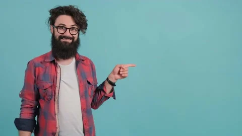 A young bearded man is pointing to the left and showing the thumb up gesture Stock Footage 139692056