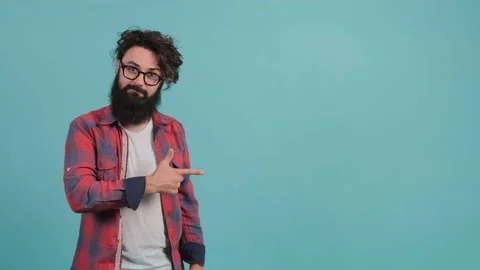 A young bearded man is pointing to the left and showing the thumb up gesture Stock Footage 140335293