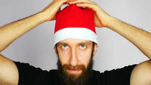 A young bearded man puts on a Christmas hat close-up Stock Footage 142215032
