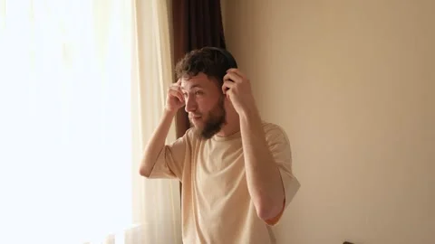 A young bearded man putting wireless headphones on his head Stock Footage 278798437
