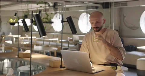 Young bearded man sitting at cafe and working on laptop Stock Footage 159082215