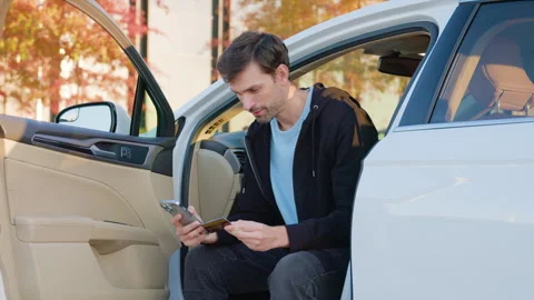 Young bearded man sitting in car, paying for car service with bank card online Stock Footage 314308281