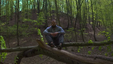 Young Bearded Man Sitting on Tree Branch and Putting on Protective Face Mask Stock Footage 130762358