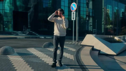 Young bearded man smiling and dancing to music in modern city Stock Footage 317554765