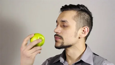 Young bearded man sniffing an apple Stock Footage 75391786