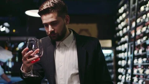 Young bearded man in a suit standing by the bar and holding a wineglass Stock Footage 74622719