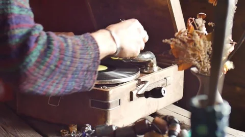 A young bearded man in a sweater involves playing on an old gramophone Stock Footage 70764059