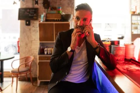 A young bearded man using the cell phone in an urban pub in the city Stock Photos