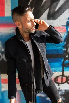 A young bearded man using the cell phone in the city Stock Photos
