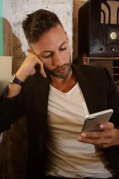 A young bearded man using the cell phone in an urban pub in the city Stock Photos