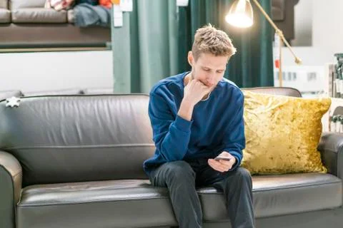 Young bearded man using smartphone sitting on the couch Stock Photos
