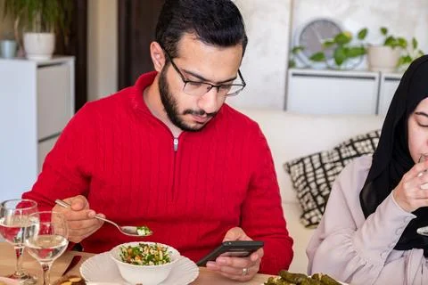 Young bearded man using smartphone while eating Stock Photos