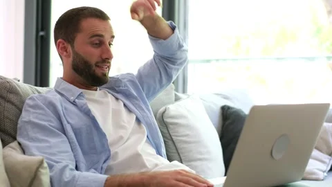 Young bearded man video chatting using laptop on sofa Stock Footage 335588579