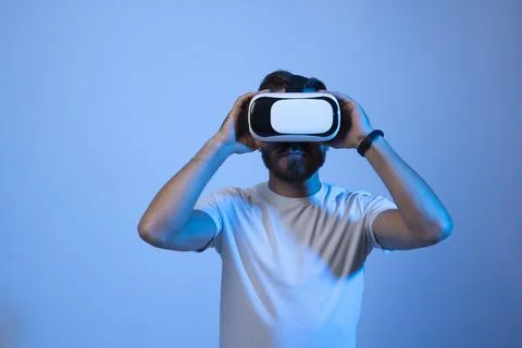 Young bearded man in virtual reality helmet plays online game in metaverse. Game Stock Photos