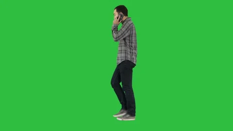 Young bearded man walking and talking on the mobile phone on a Green Screen Stock Footage