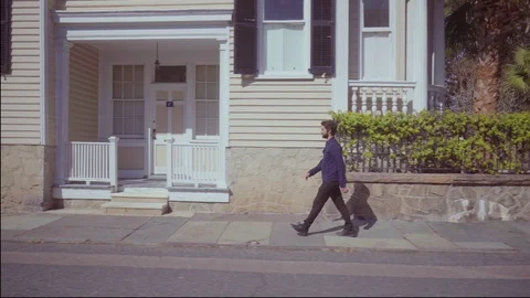 Young bearded man walking down the street along houses Stock-Footage 105313517