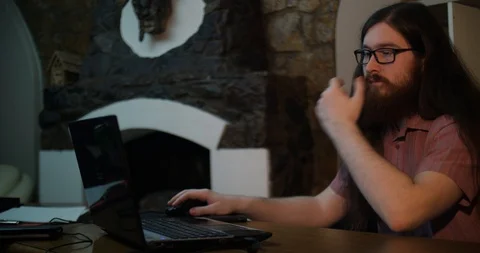 Young bearded man wearing glasses working with laptop in dark office late at 動画素材 87323190