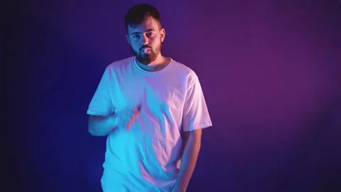 Young bearded man in a white t-shirt holds an electronic cigarette in his hand 库存影片 144342114