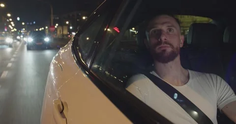 Young bearded man in white t-shirt is traveling by taxi in the night with the Stock Footage 202018106