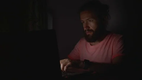 Young bearded man working on laptop in darkness Stock Footage 104547809