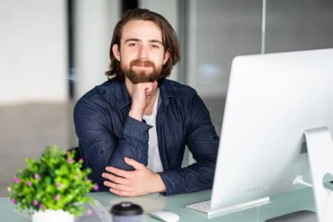 Young bearded man working at xomputer in modern office Stock Photos