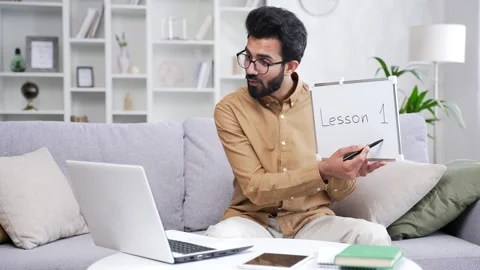 Young bearded school teacher conducts an online lesson via video call using  Stock Footage 252206478
