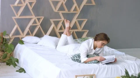 Young beatiful woman relaxing at home while reading on the bed at home. Stock Footage