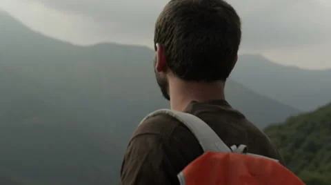 Young beautiful beard man on mountain with a red vintage backpack Video stock 64516225
