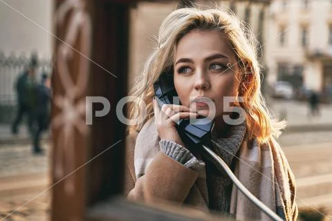 Young beautiful blond woman making an important call in a vintage public phone Stock Photos