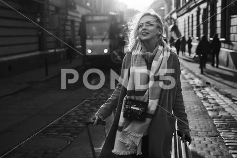 Young beautiful blond woman tourist with a wheeled travel bag and vintage film Stock Photos