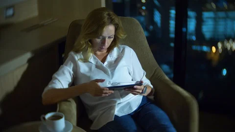 Young, beautiful blond woman using a tablet pc on a chair in a room Stock Footage 86206204