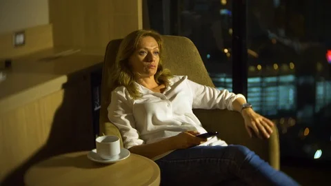 Young, beautiful blond woman using a tv control panel, on a chair Stock Footage 86399761