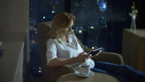Young, beautiful blond woman using a tablet pc, on a chair in a room Stock Footage 86903882