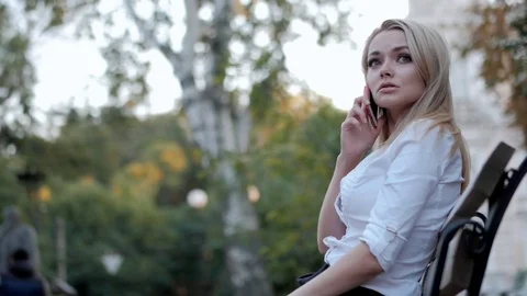 Young beautiful blonde businesswoman talking by mobile phone while sitting on Stock Footage