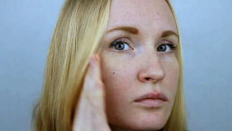 A young beautiful blonde looks at the cheek on which the pimple appeared. Stock Footage 87561853