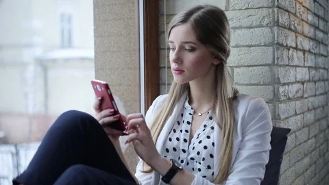 Young beautiful blonde start-upper sits near the window using phone Stock Footage 73184835