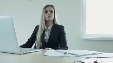Young beautiful blonde is thinking in the office at the table in front of the Stock Footage 74699962