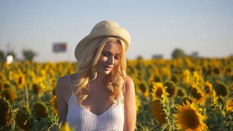 Young beautiful blonde woman running in sunflower field. Sunset background. Sexy Stock Footage