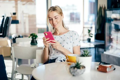 Young beautiful blonde woman smiling uses social media in a mobile phone. Stock Photos