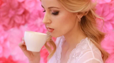Young beautiful bride drinking from white cup on pink flowers background Stock Footage 53799105