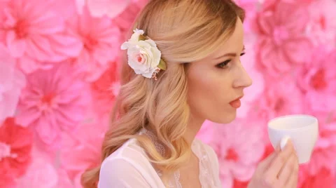Young beautiful bride drinking from white cup on pink flowers background Stock Footage 53799122