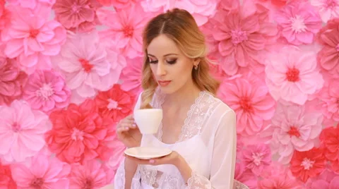 Young beautiful bride drinking from white cup on pink flowers background Stock Footage 53799135