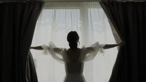 A young beautiful bride opens the curtains Video stock 328185564