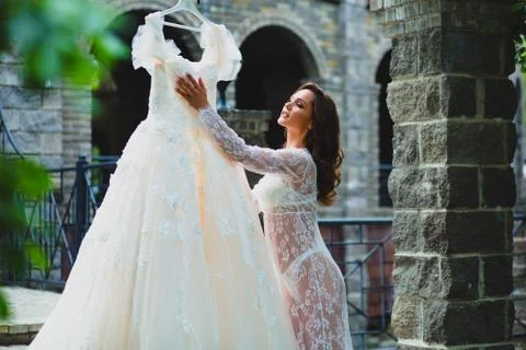Young beautiful bride preparing to try on her luxury bridal dress Stock Photos
